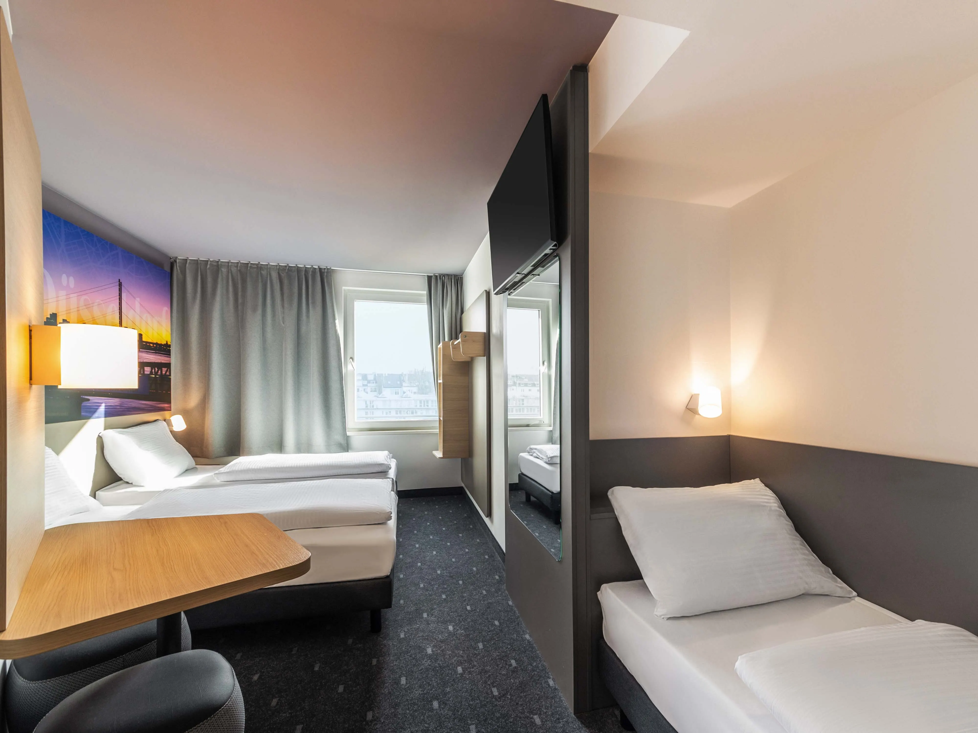 Szeroki kadr pokoju B&B Hotels z łóżkami, lustrem i zabudową